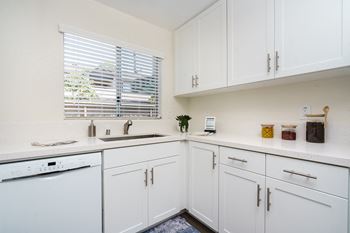 a kitchen with white cabinets and a white dishwasher